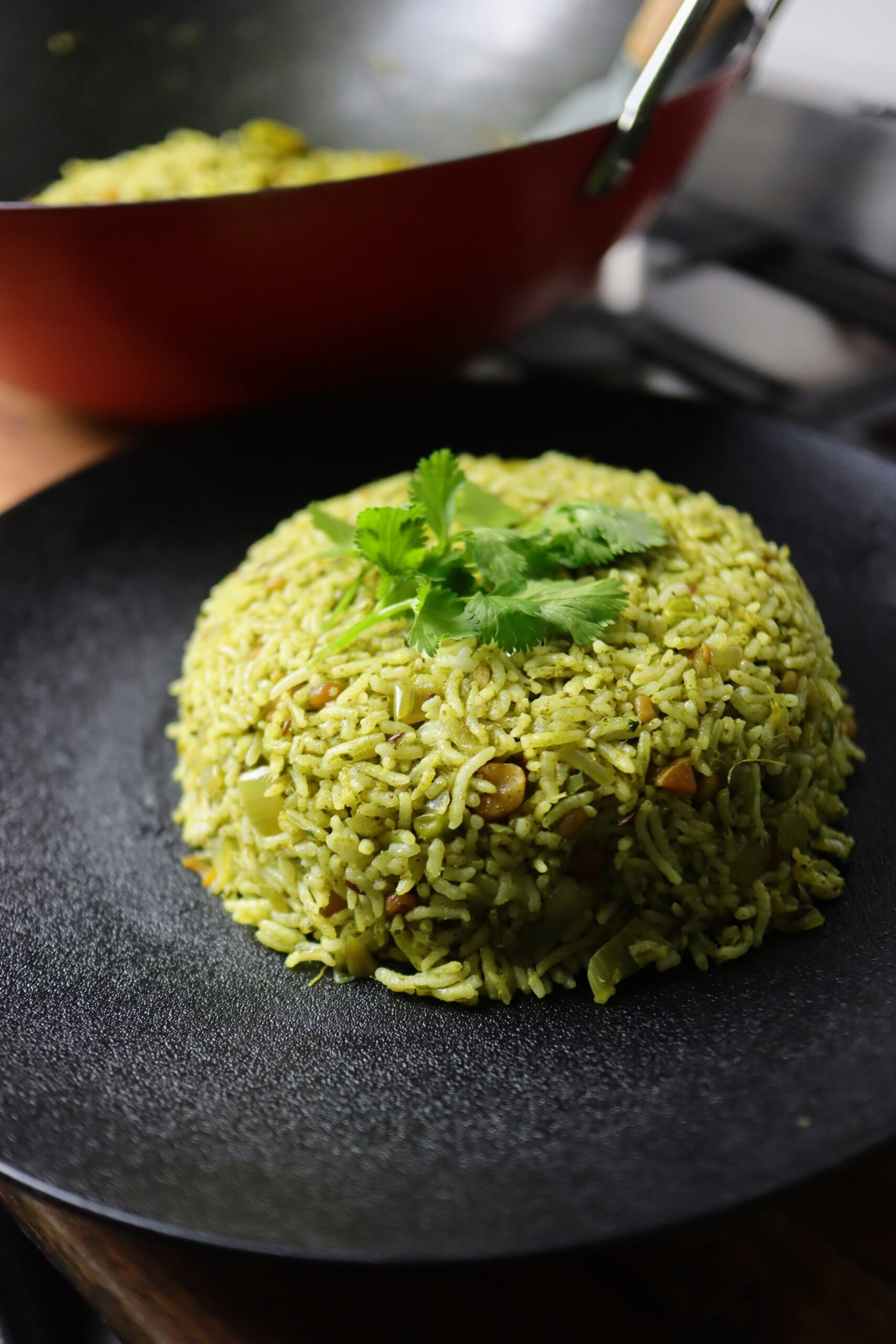 Close-up of a white plate filled with fluffy, green coriander rice