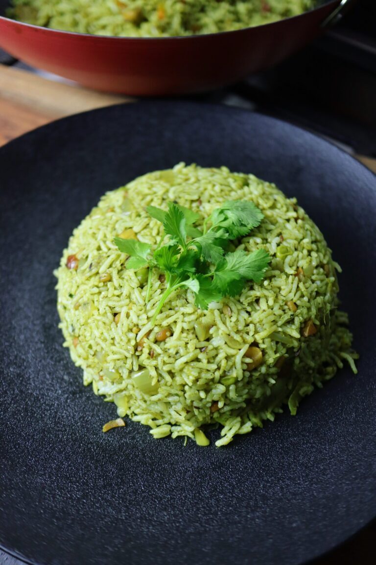 Close-up of a white plate filled with fluffy, green coriander rice