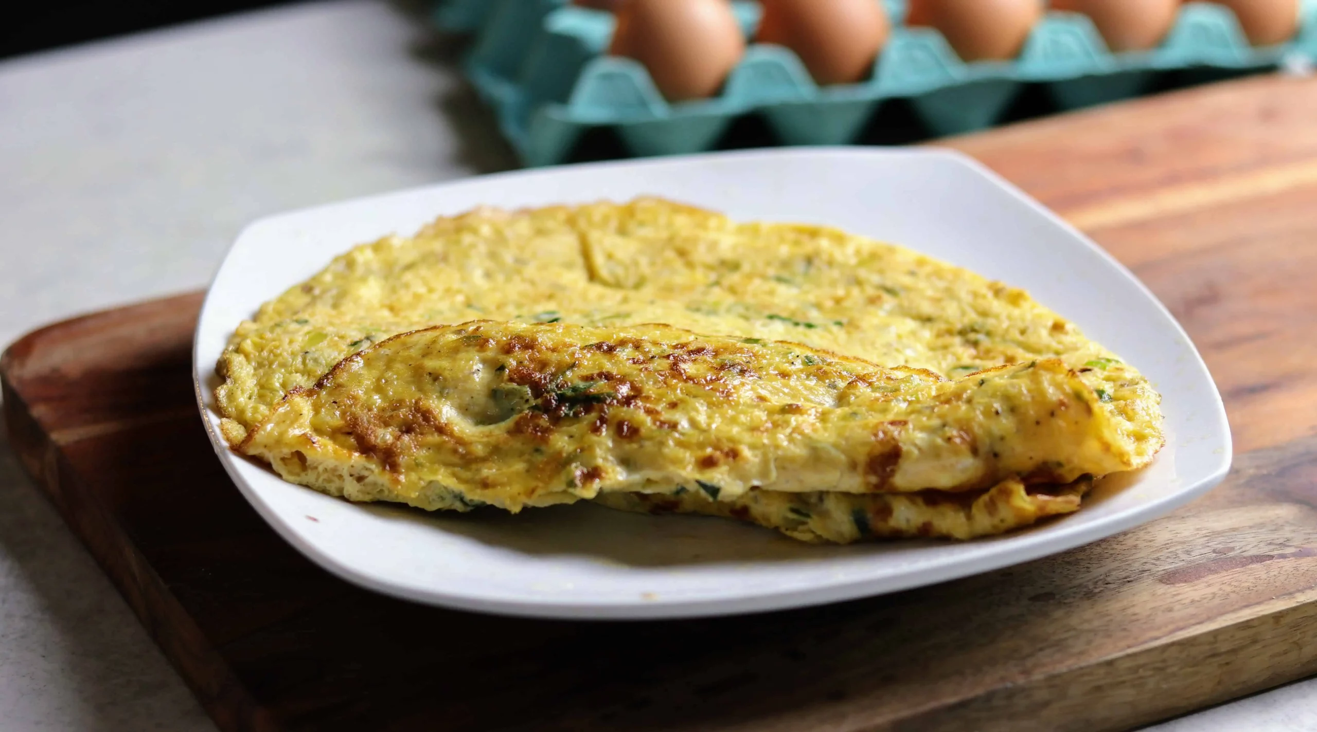 A freshly made, fluffy Indian omelette sits folded in half on a plate