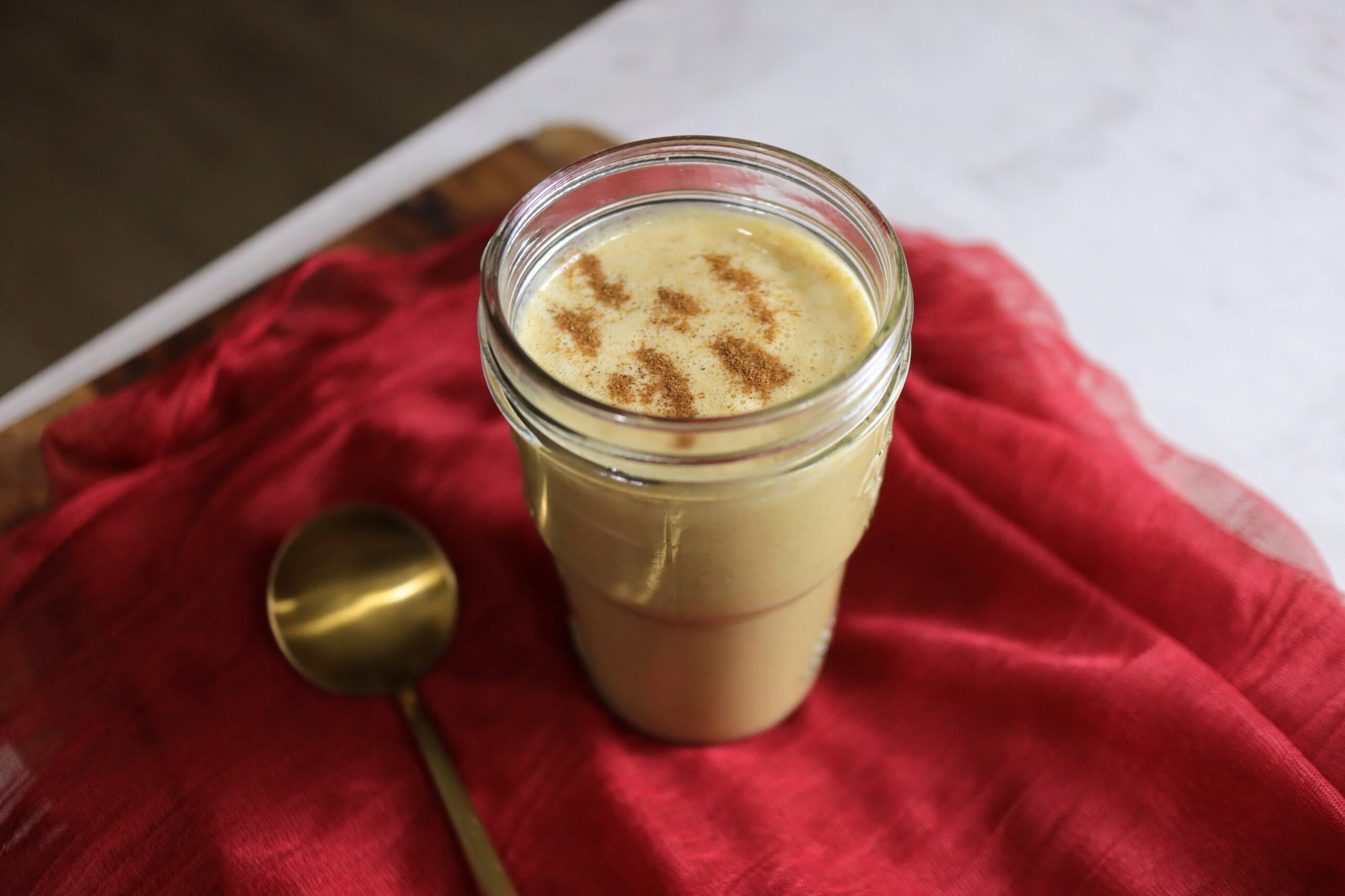 A glass jar with a spoon and cinnamon, ready to spice up your post-run nut butter smoothie.