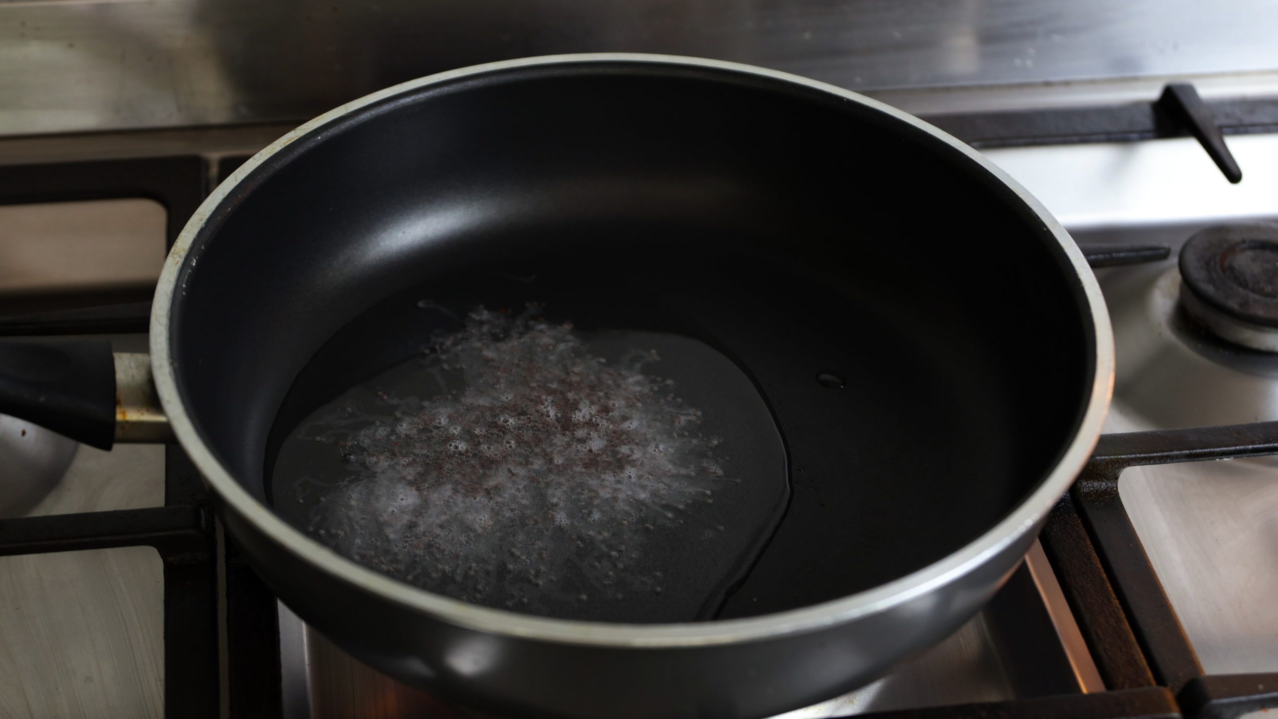 sauce pan with coconut oil and mustard seeds added for making kale stir fry