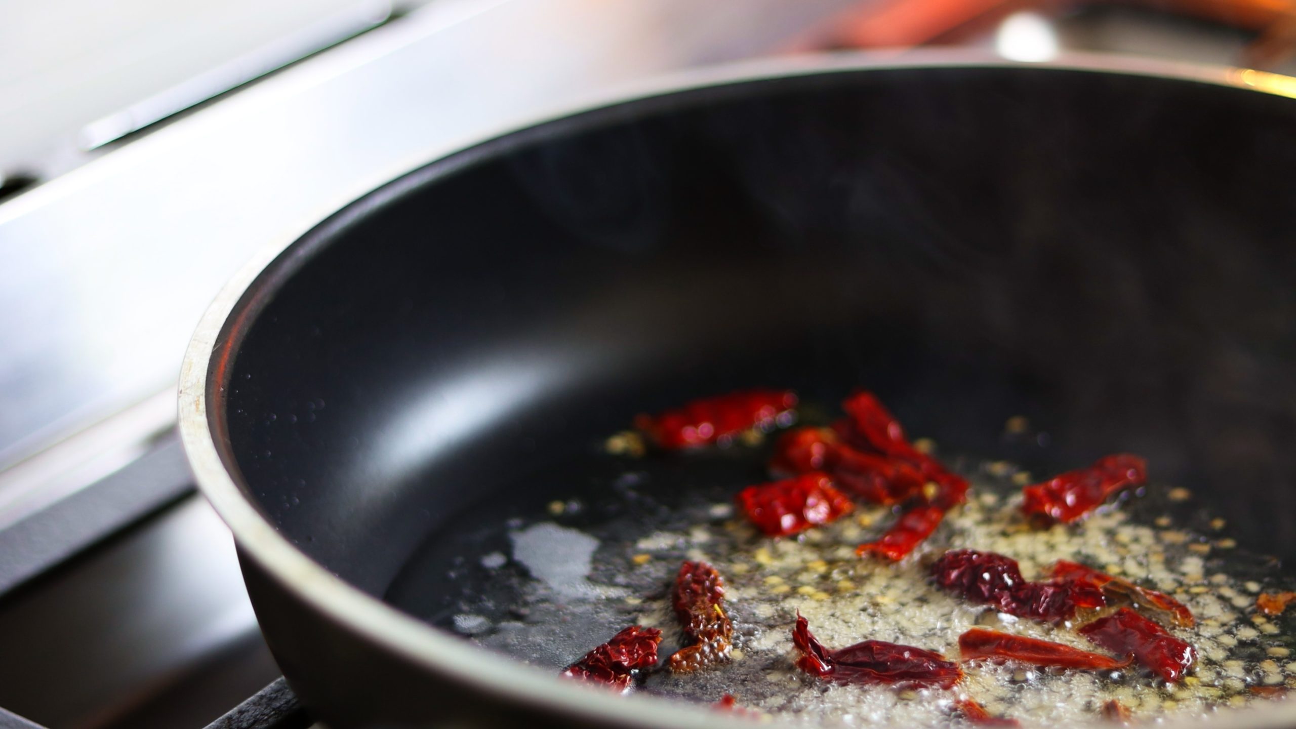 sauce pan with coconut oil and mustard seeds, urad dal, red chillies added for making kale stir fry