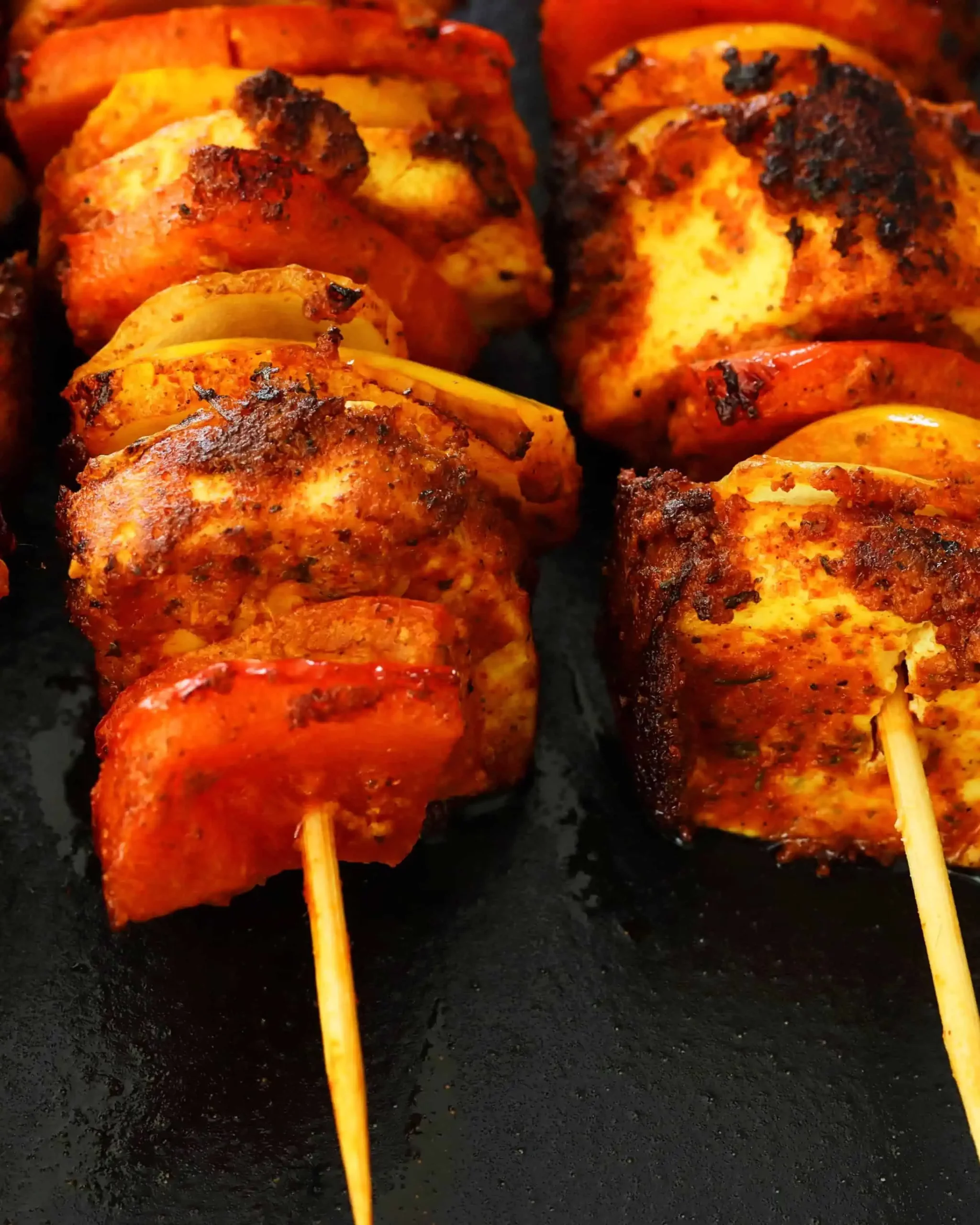 Close-up of flavorful skewers featuring paneer tikka, bell peppers, and onions.