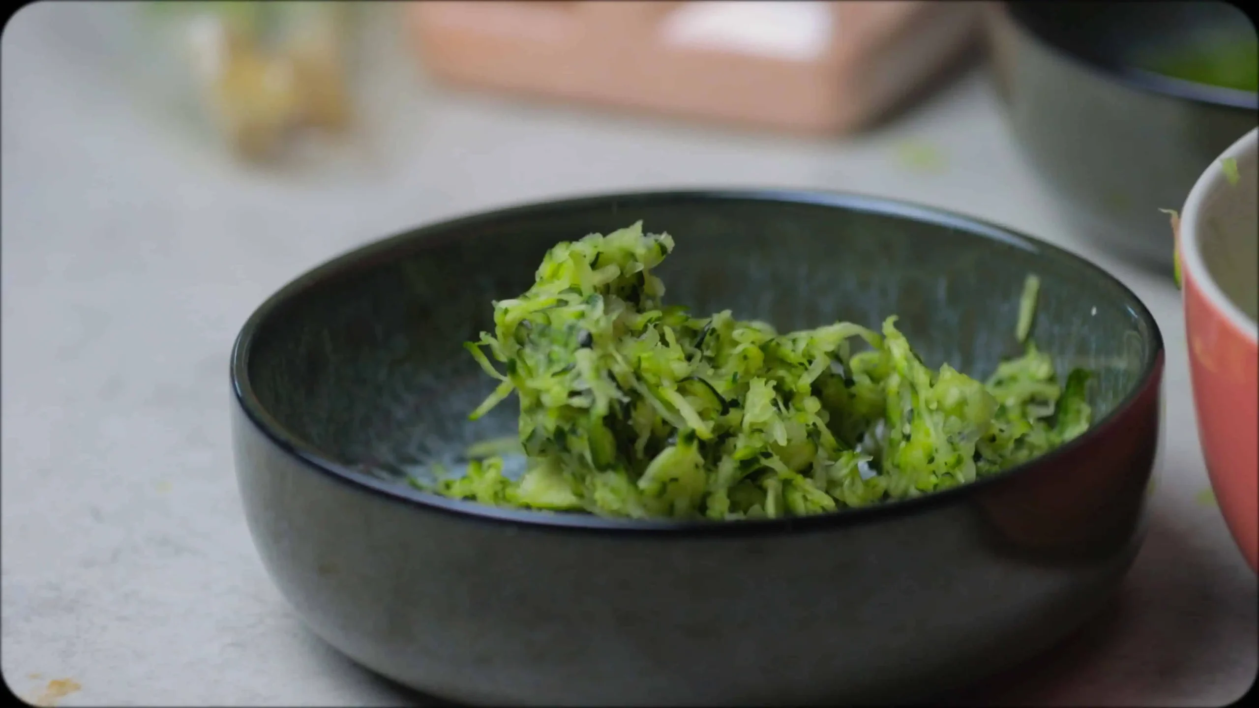 Fresh ingredients for zucchini fritters laid out on wooden surface: grated zucchini, eggs, chickpea flour, and aromatic spices