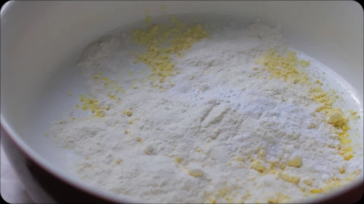 Bowl of zucchini fritter batter showing combined ingredients with visible herbs and spices