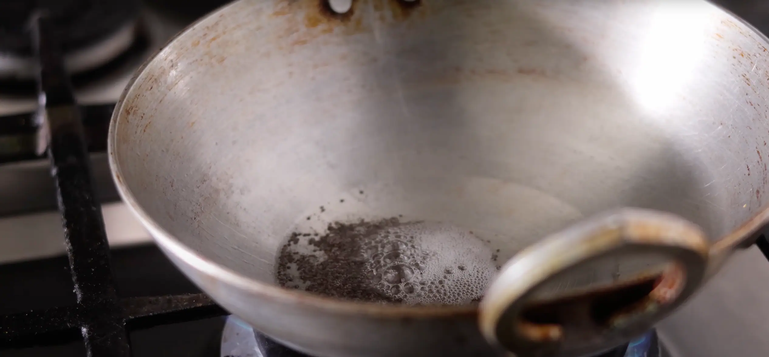 adding spices to a kadai for making aratikaya kura