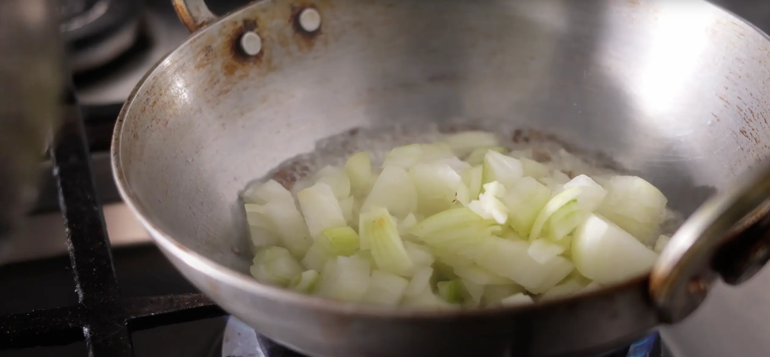 adding onions to a kadai for aratikaya kura recipe